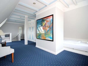 A room with a blue carpet, a painting on the wall, and a staircase. - Island Love OG W3 (Sylt)