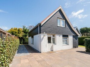 A single-story house with a gabled roof, a small front porch, and a paved driveway. - Holiday Home in Renesse With Swimming Pool (Renesse)