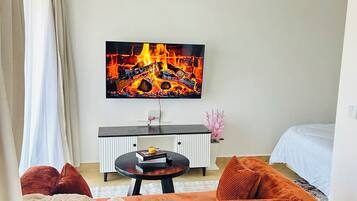 A modern living room with a flat-screen TV, a round wooden coffee table, and a sofa.