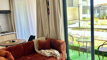 A modern living room with a sofa, a coffee table, and a view of an outdoor garden through a large window.