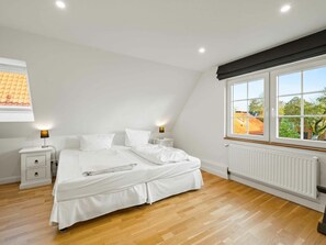 A bedroom with a bed, bedside tables, a window, and a radiator. - Holiday Home With 2 Bedrooms (Krummhoern)
