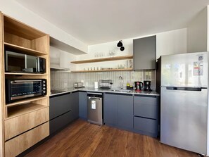 Eine moderne Küche mit integrierten Geräten, Holzböden und einem Edelstahlkühlschrank.