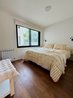 Ein Schlafzimmer mit einem großen Bett, einem Fenster, einer Heizung und einem weißen Stuhl.