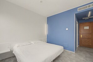 A bedroom with a single bed, a wooden door, and a blue accent wall. - Standard Double Room with WiFi and Air Conditioning (Dolo)