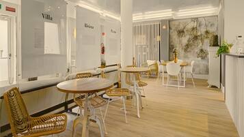 A modern interior with round tables and wicker chairs, white walls, and a wooden floor.