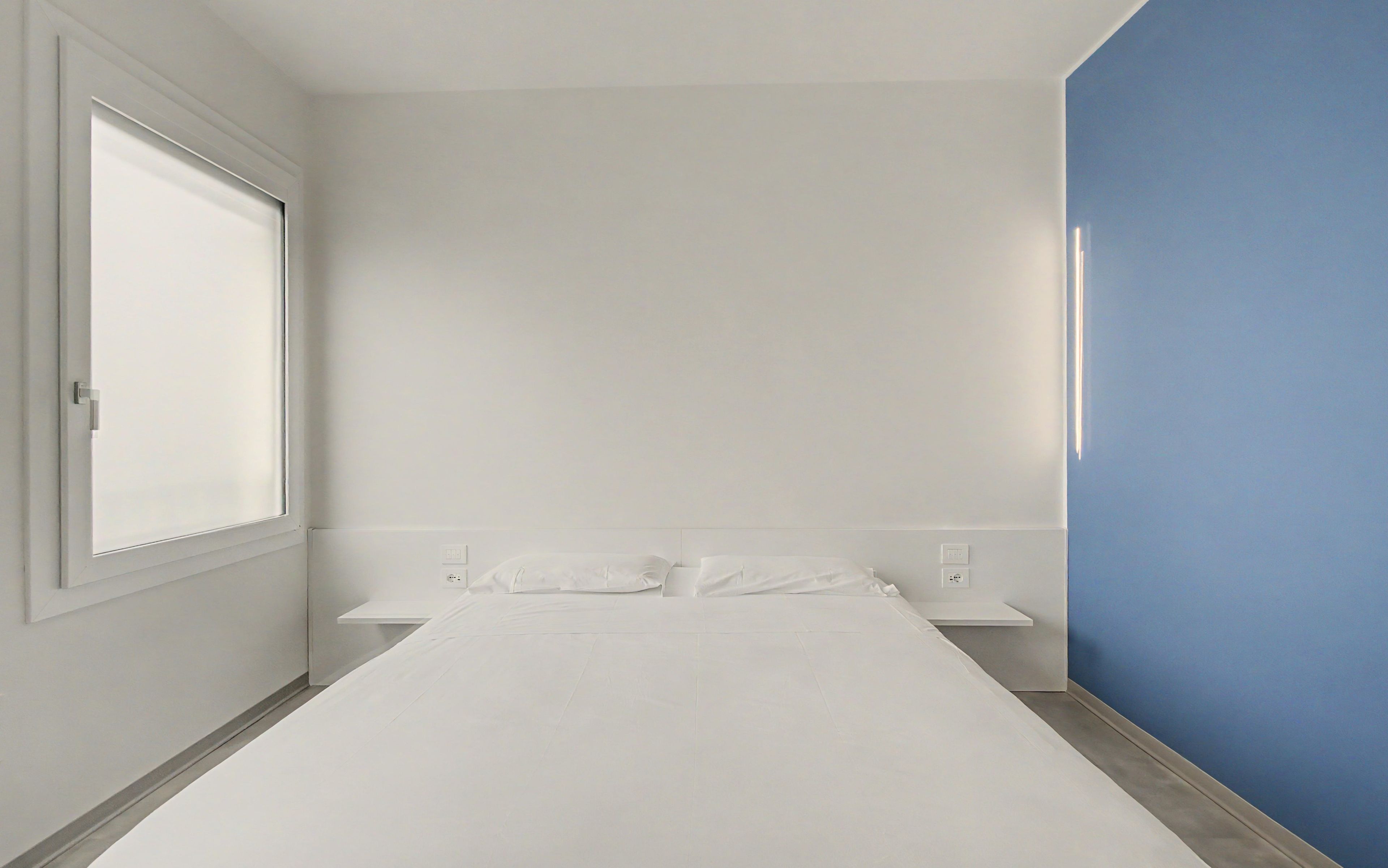 Une chambre à coucher avec un lit, une fenêtre et un mur bleu.