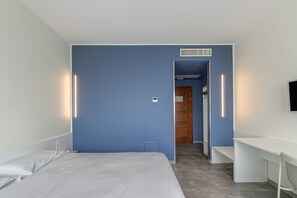 A hotel room with a bed, a desk, and a TV.
