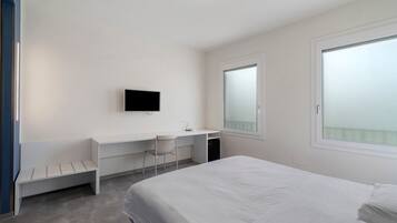Une chambre d’hôtel moderne équipée d’un lit, d’un bureau, d’une chaise, d’une télévision et d’une fenêtre.