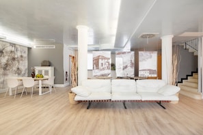 Ein modernes Wohnzimmer mit einem weißen Sofa, einem Esstisch mit Stühlen und einer Treppe.