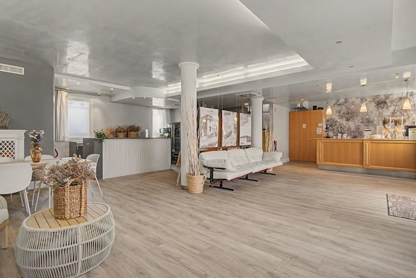Une pièce spacieuse dotée d’un plancher en bois, d’un canapé blanc, d’un coin repas avec une table et des chaises, et d’un coin cuisine avec des meubles en bois.