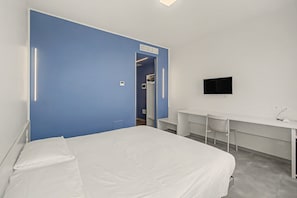 Une chambre d’hôtel avec un grand lit, un bureau avec une chaise, une télévision et une armoire.