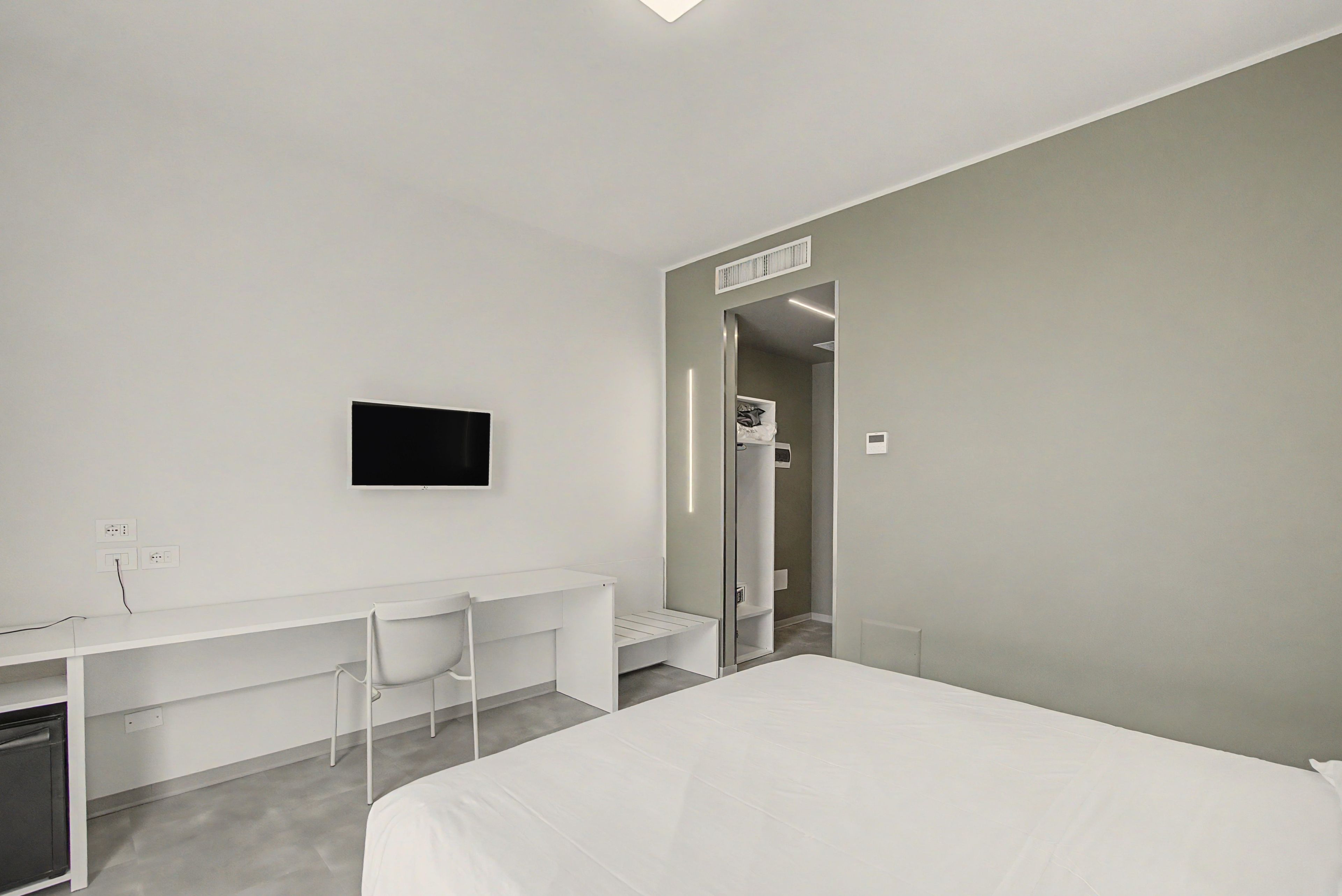 Une chambre d’hôtel équipée d’un lit, d’un bureau, d’une chaise, d’une télévision et d’une armoire.