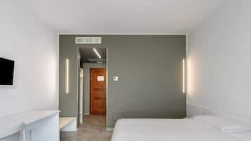 Ein modernes Hotelzimmer mit einem Bett, einem Schreibtisch und einem an der Wand befestigten Fernseher.