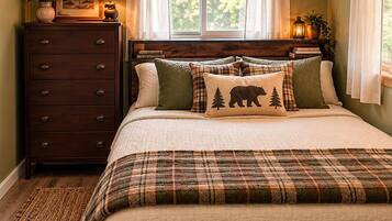 A bedroom with a bed, a dresser, a window with curtains, and a nightstand with a lamp.