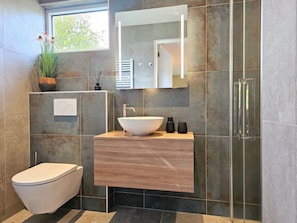 Ein modernes Badezimmer mit einem großzügigen Aufsatzwaschbecken, einer Toilette und einer Duschkabine.