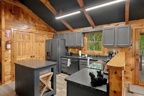 Una cocina moderna con paredes de madera, una isla central y una ventana con vistas a zonas verdes.