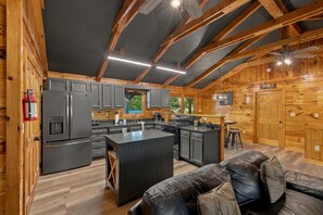 Una cocina moderna con una isla central, vigas de madera y un sofá de cuero negro.