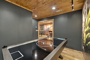 Una mesa de billar con estructura de madera, una pared gris y un techo de madera.