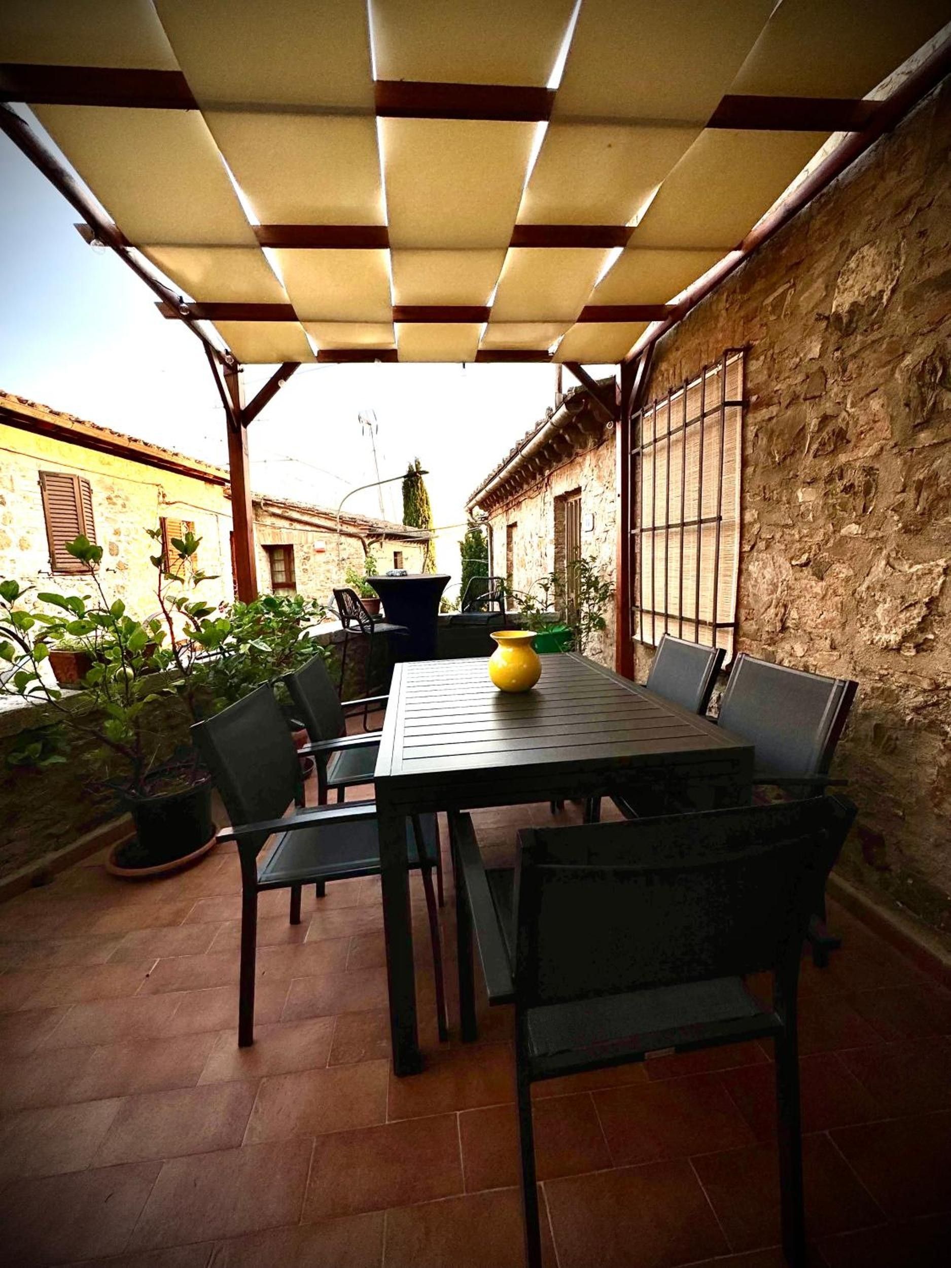 Une terrasse extérieure avec une table et des chaises, un vase jaune et des plantes en pot.