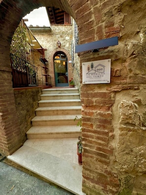 Un escalier en pierre mène à l’entrée d’un immeuble où une enseigne indique : « LA NOBILTA DEL TEMPO CASA VACANZA ».