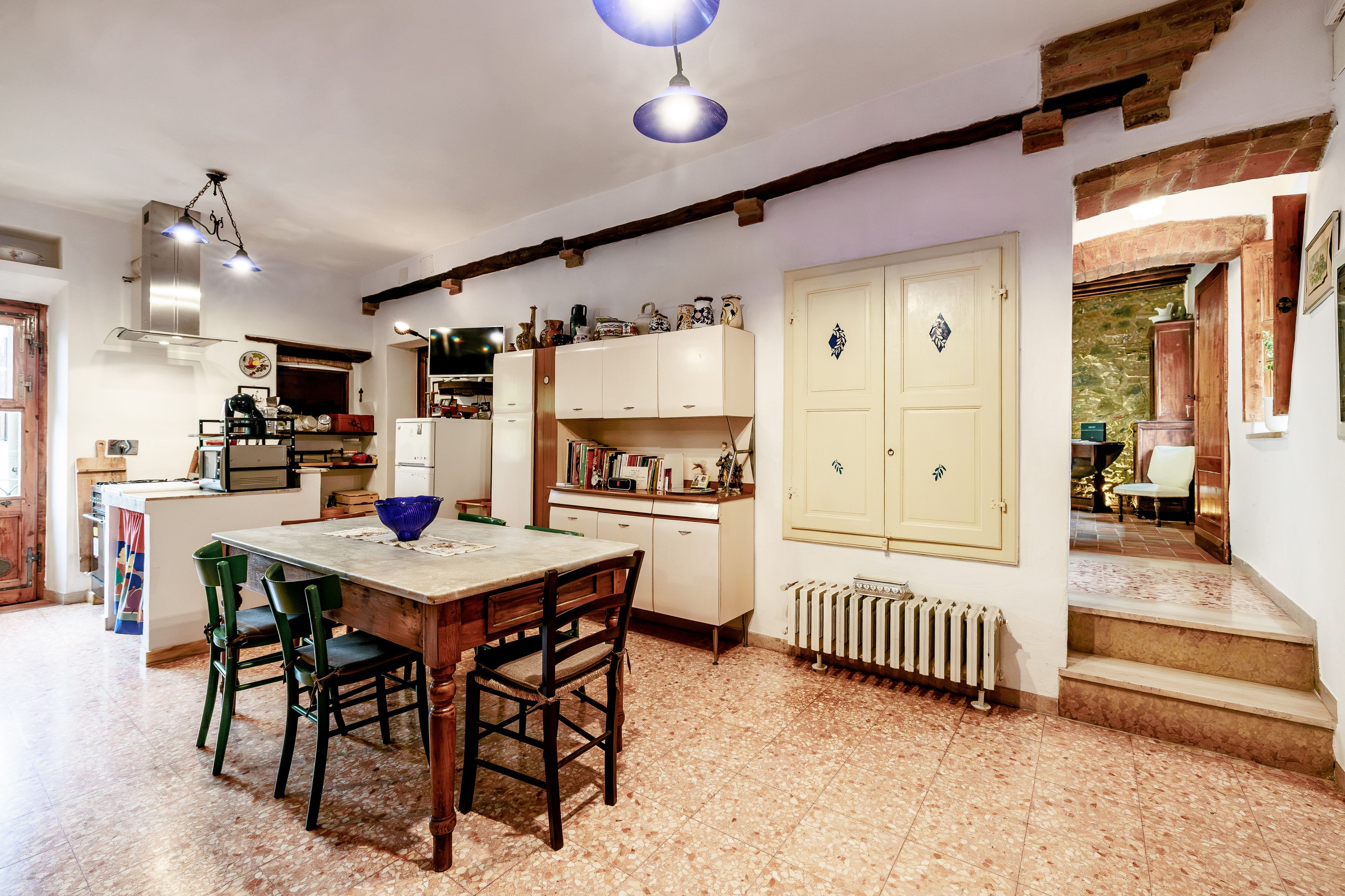 A kitchen with a dining table, chairs, a blue bowl, and a radiator.