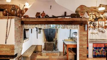 Una cucina rustica con un tradizionale stufa, pentole appese e una panca di legno.