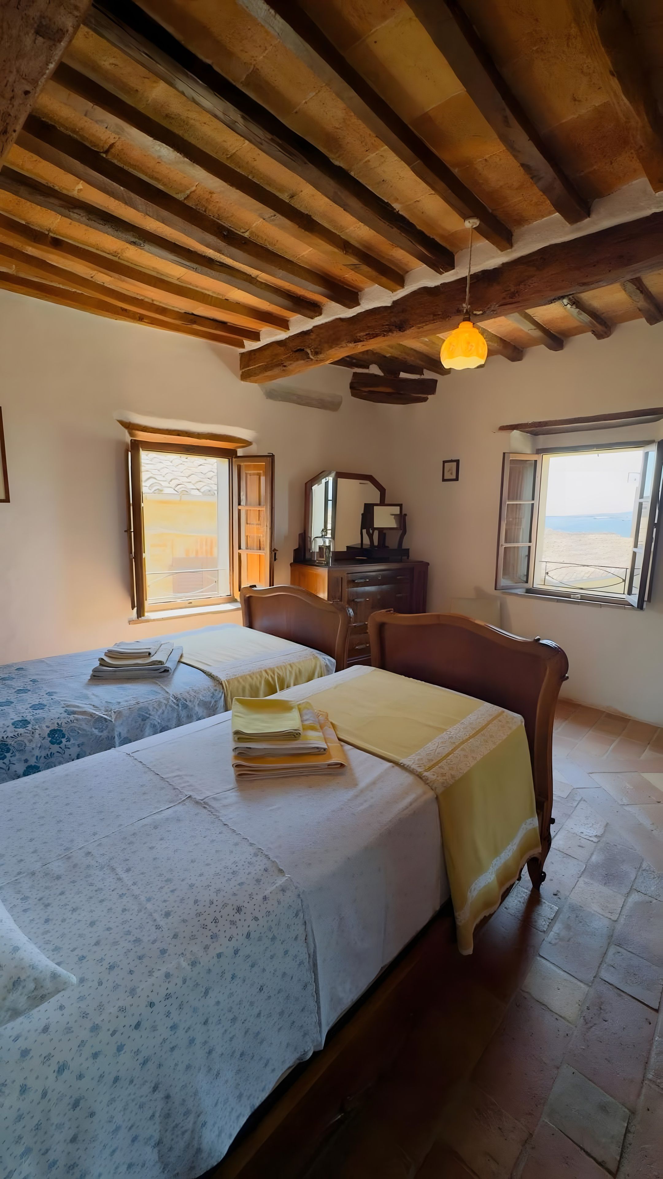 Une chambre avec un lit, une chaise, une commode et une fenêtre donnant sur un beau paysage.
