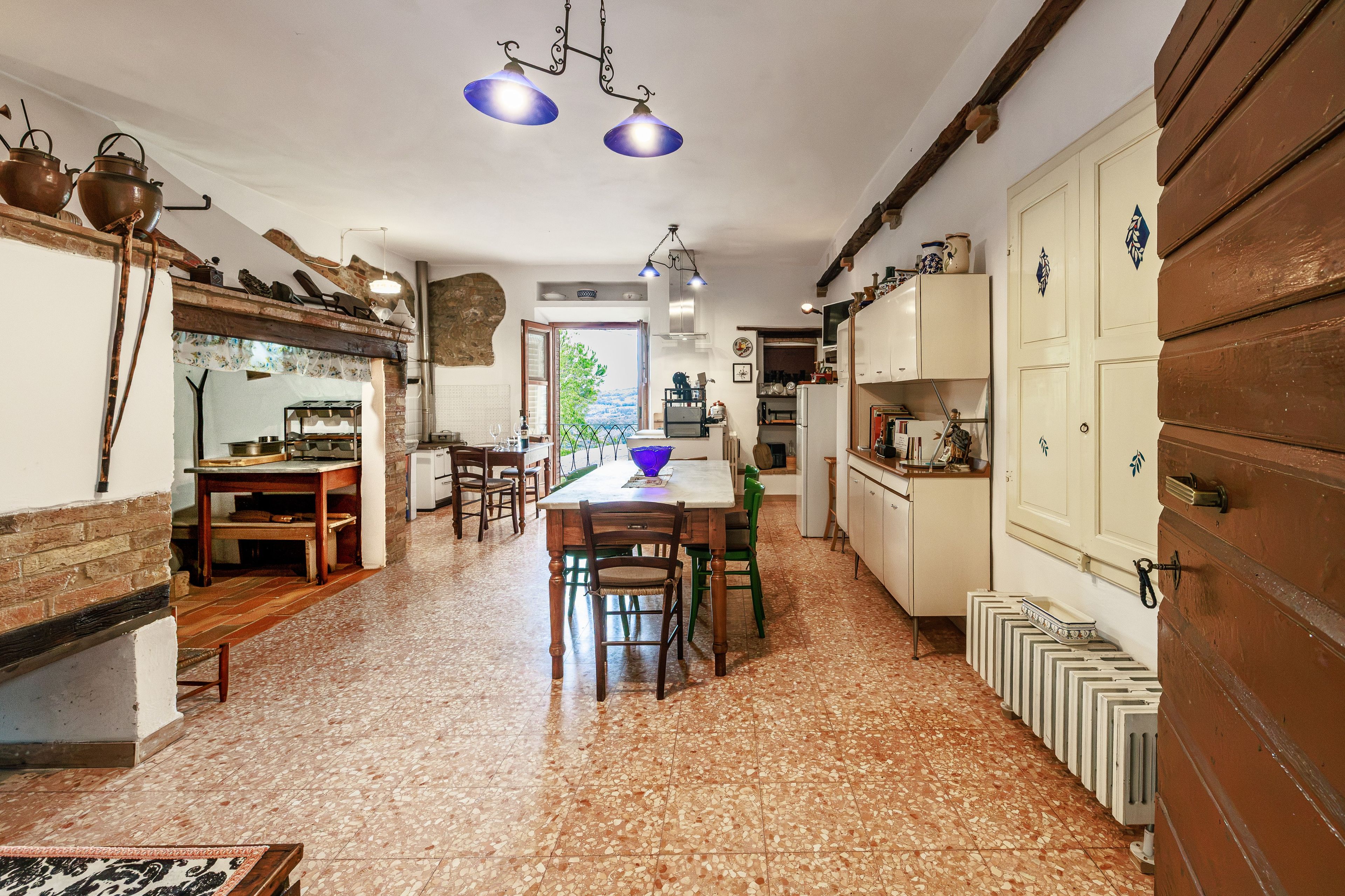 A kitchen with a dining area, wooden cabinets, and a tiled floor.
