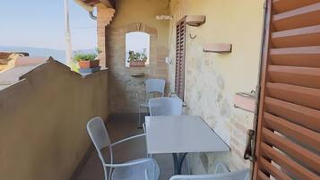 Un balcon avec une table et des chaises, un pot de fleurs et une vue sur le ciel.