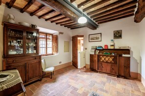 A room with exposed wooden beams, a radiator, a cabinet with glass doors, and a chair.
