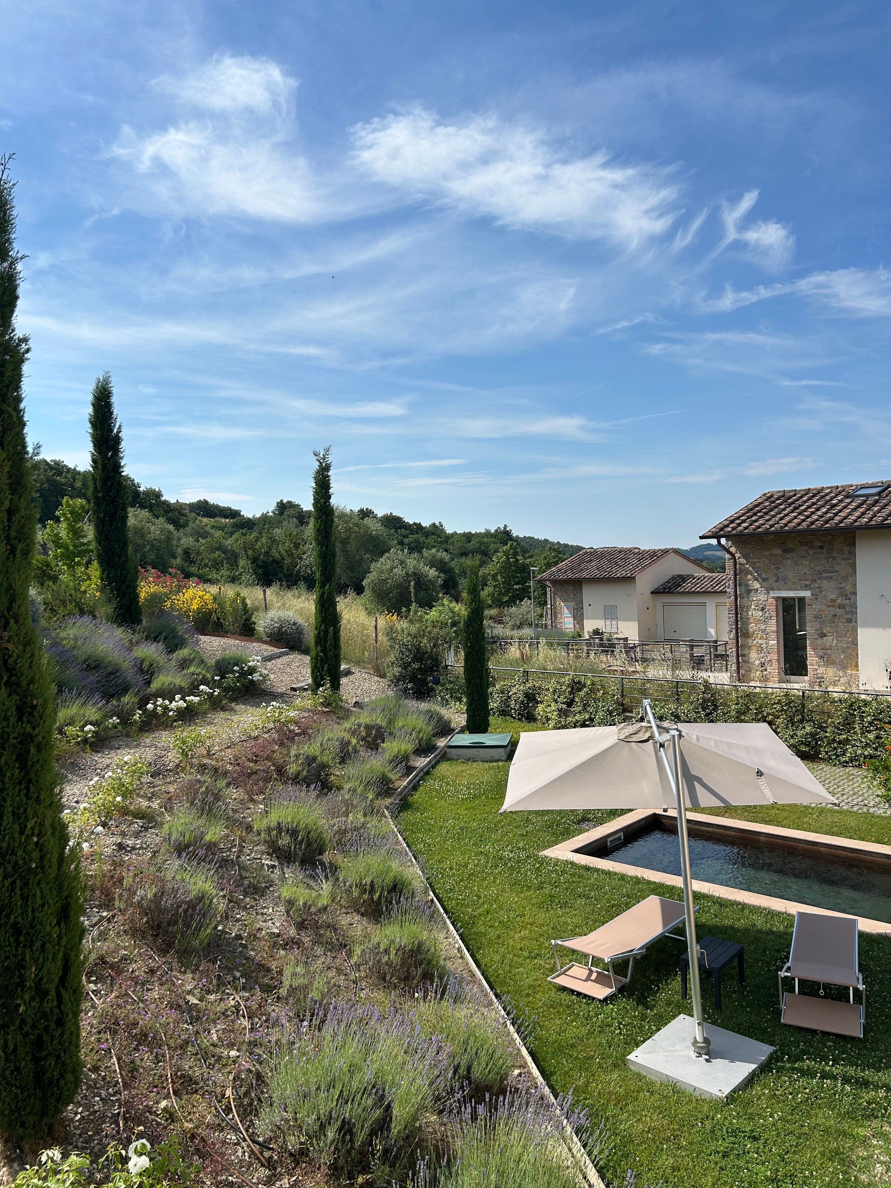 Un giardino con piscina, mobili da esterno e una casa con tetto in tegole.