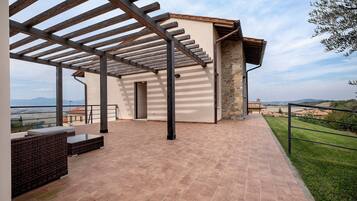 Ein überdachter Patio-Bereich mit einer Pergola, Sitzgelegenheiten im Freien und Blick auf die Landschaft.