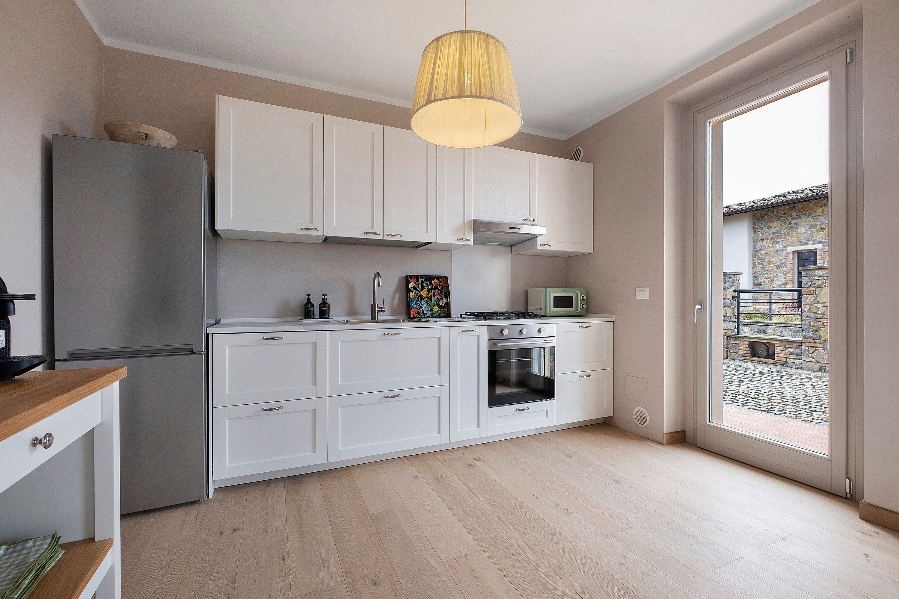 Une cuisine moderne avec des meubles blancs, un four encastré et un four à micro-ondes.