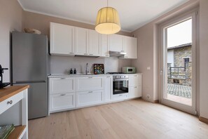 A modern kitchen with white cabinets, a built-in oven, and a microwave.