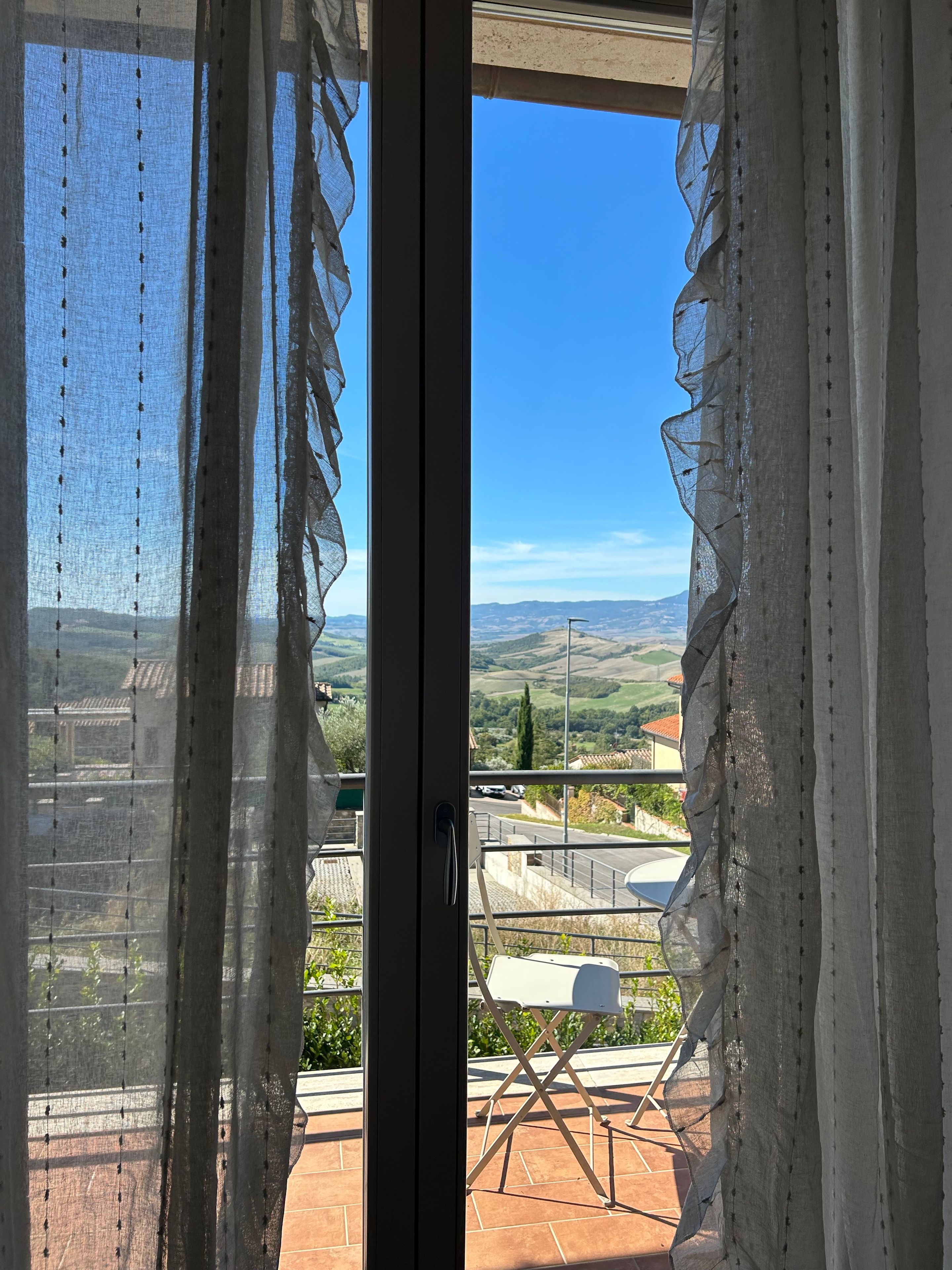 A view from a balcony with a clear sky, a white chair, and a metal railing.