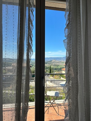A view from a balcony with a clear sky, a white chair, and a metal railing. - Villa 'San Casciano' with Village View and Private Pool (San Casciano dei Bagni)