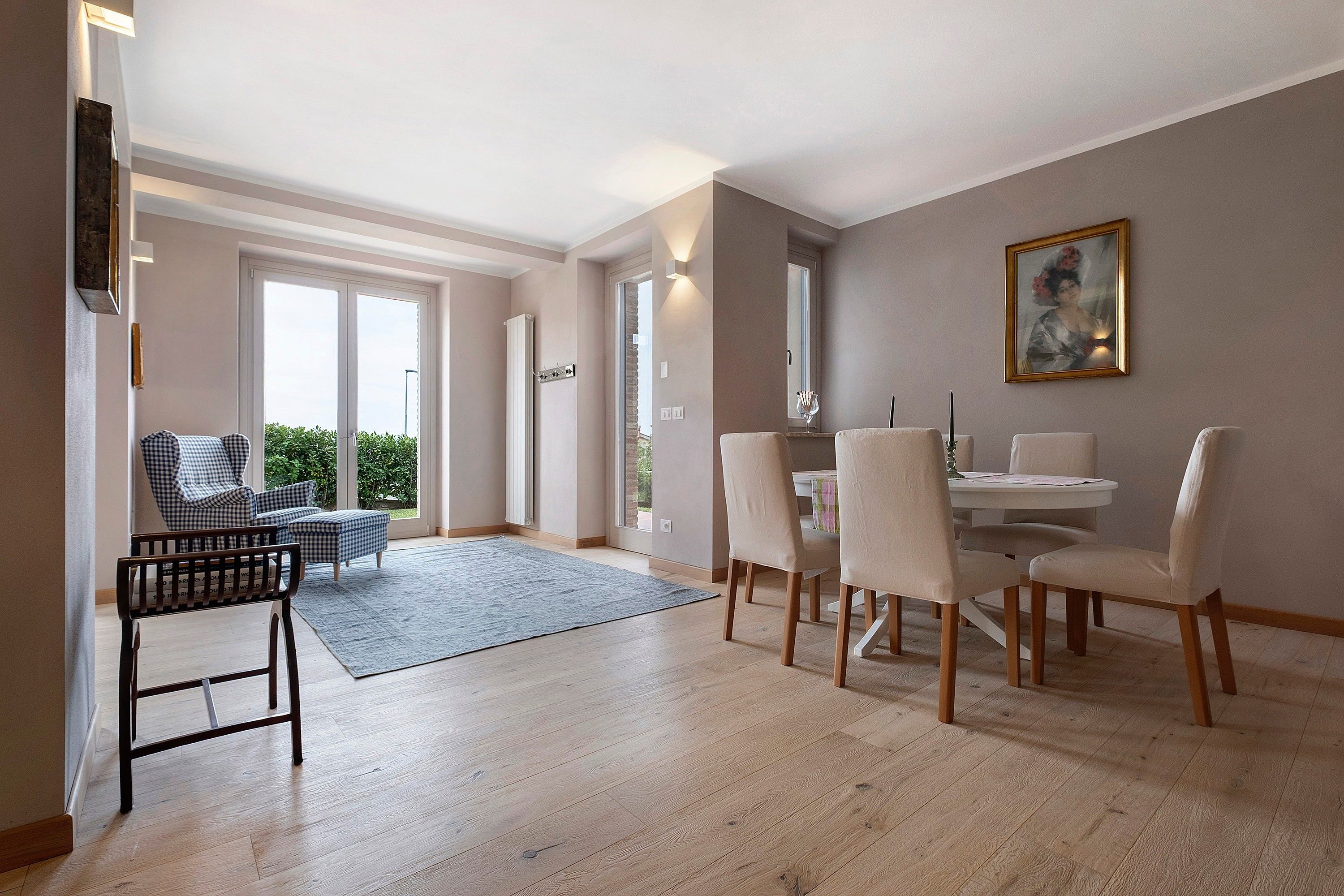 Un espace repas comprenant une table et des chaises, un canapé et une vue à travers une porte vitrée.