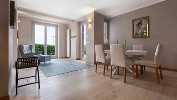 Un espace repas comprenant une table et des chaises, un canapé et une vue à travers une porte vitrée.