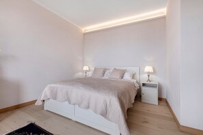 A bedroom with a bed, bedside lamps, and a nightstand.