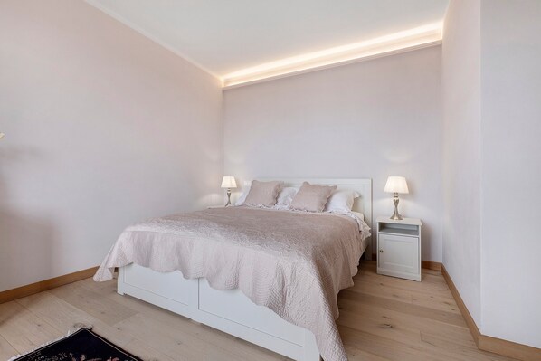A bedroom with a bed, bedside lamps, and a nightstand.