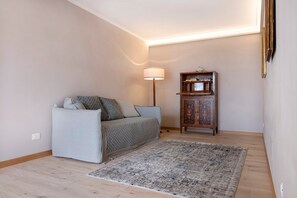 A room with a sofa, a rug, a lamp, and a wooden cabinet.