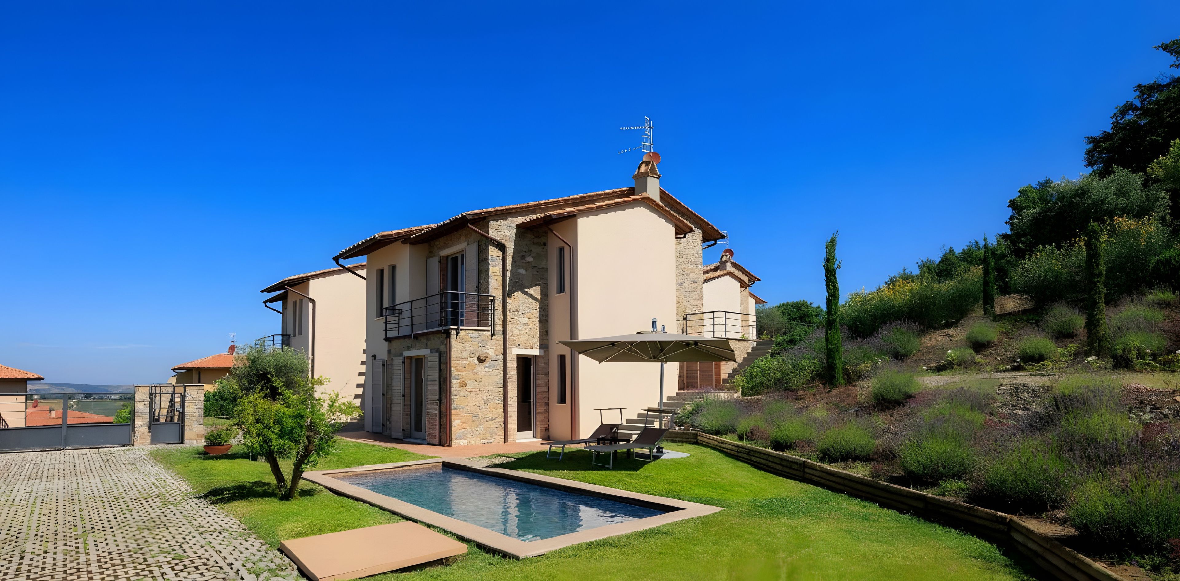 Ein zweistöckiges Haus mit Schwimmbad, einer überdachten Terrasse und Blick auf die umliegende Landschaft.