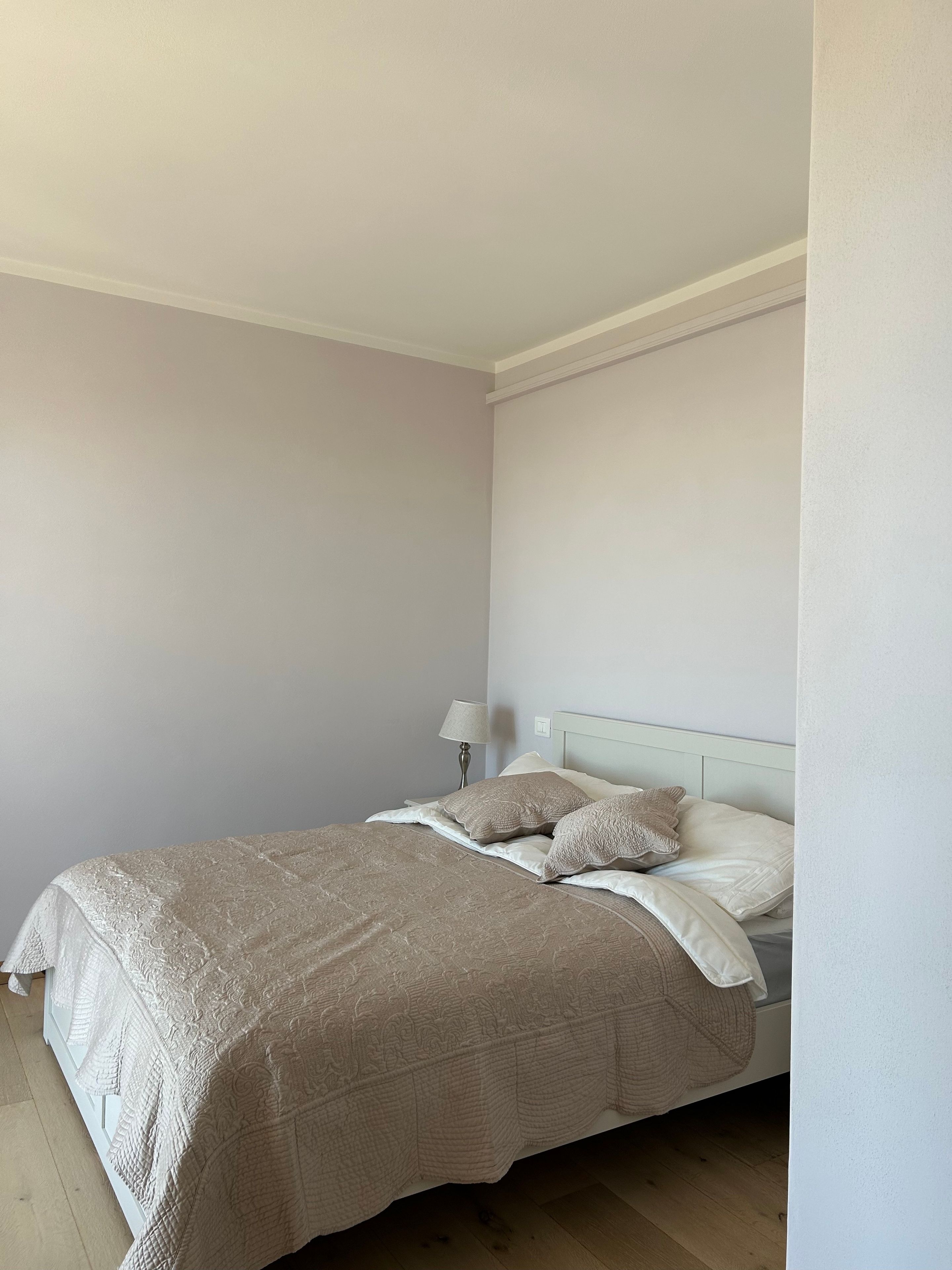 Ein Schlafzimmer mit einem Bett, Kissen, einem Nachttisch und einer Lampe.