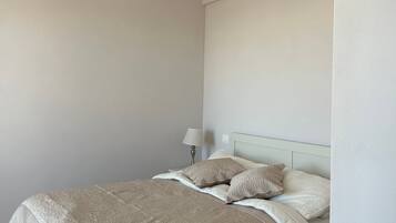 Ein Schlafzimmer mit einem Bett, Kissen, einem Nachttisch und einer Lampe.