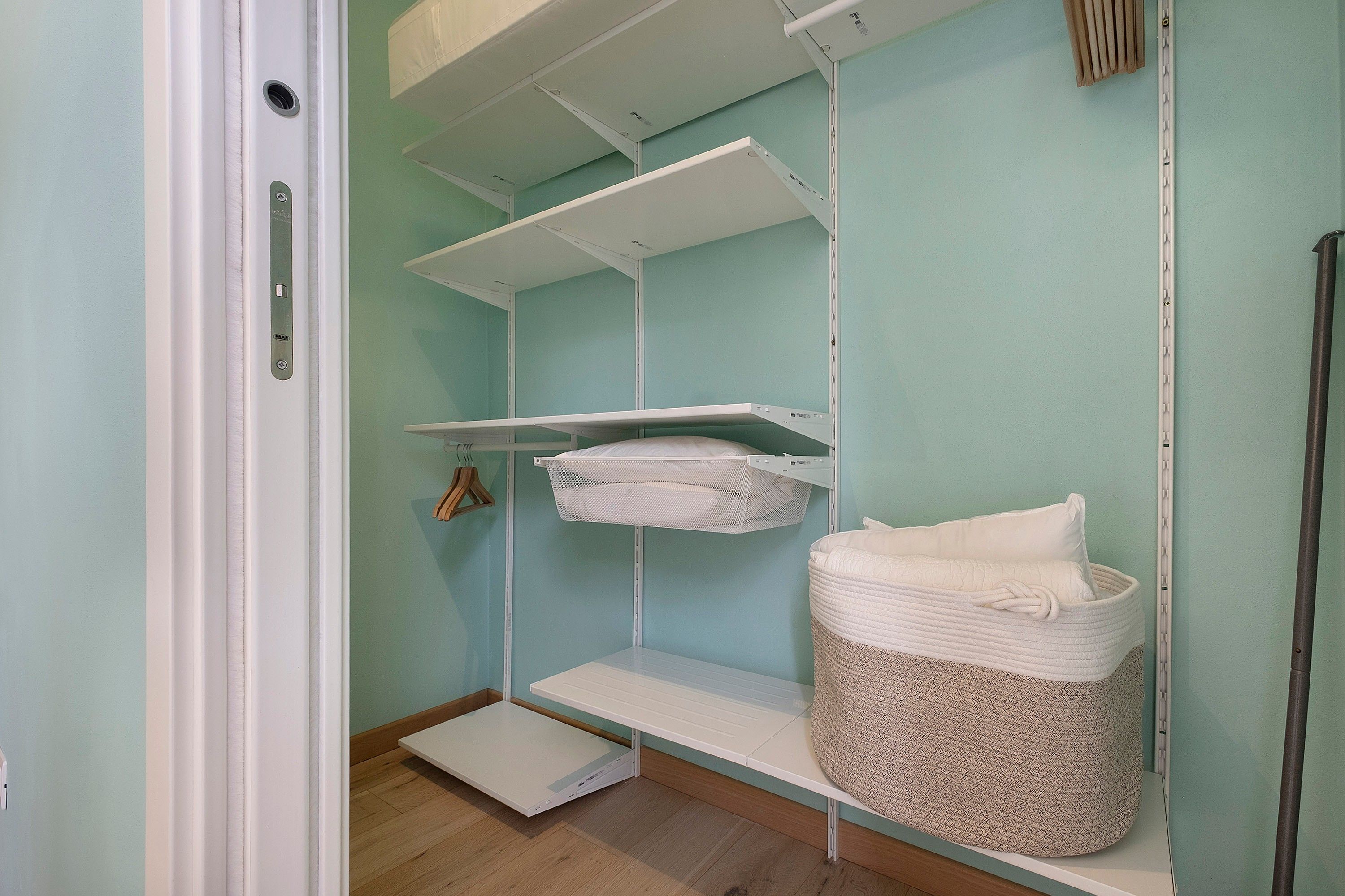 Una habitación con estantería empotrada, una pequeña cesta de almacenamiento y una puerta con manija.