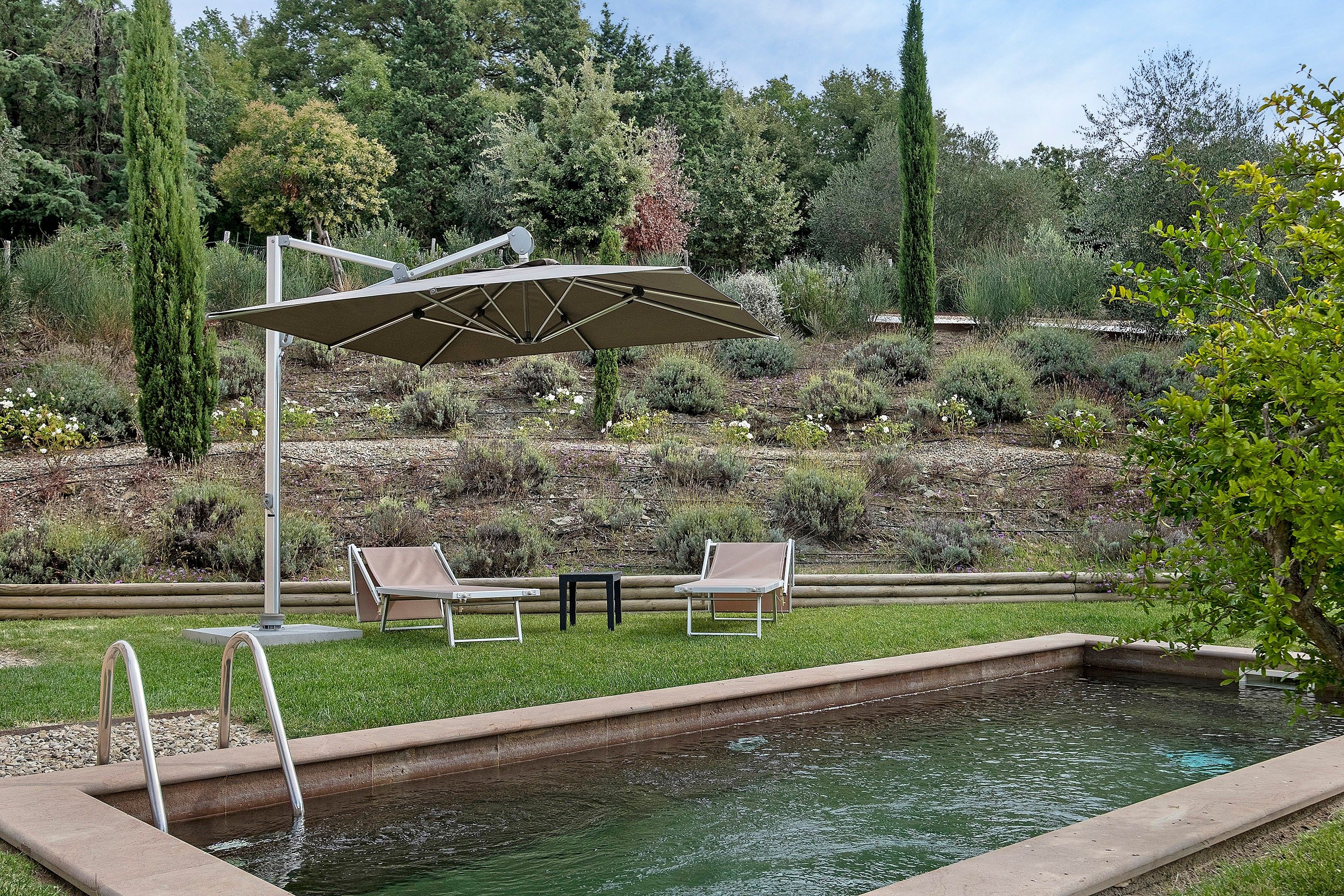 Un espace piscine agrémenté d’une pergola, de deux chaises longues et d’une petite table.