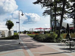 A paved walkway with a directional sign for toilets, surrounded by trees and outdoor seating areas. - Holiday Home in Glowe With Swimming Pool (Glowe)