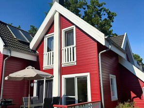 A red building with two windows and a covered patio area. - Holiday Home in Glowe With Swimming Pool (Glowe)