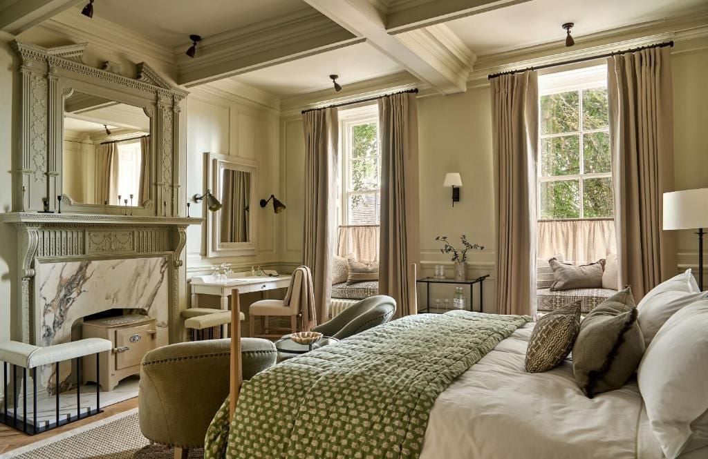 Una habitación de hotel clásica con cama, zona de estar, tocador y chimenea.