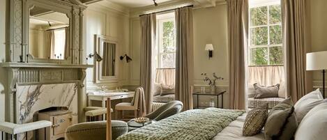 Una habitación de hotel clásica con cama, zona de estar, tocador y chimenea.